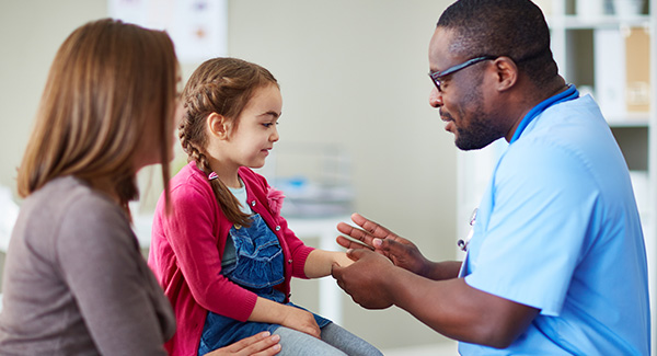 Doctor talking to little girl with mother next to her.